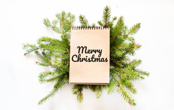 istock Brown notepad lying on branches of a christmas tree with text Merry Christmas 1282038168