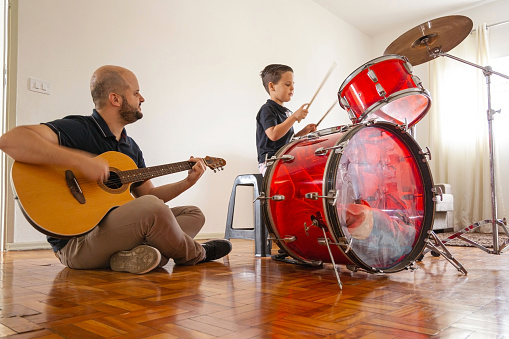 Photo of father and son playing music at home.