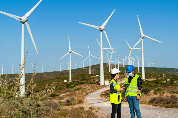 istock Technical businessman wearing protective face mask working in COVID-19 outbreak after novel coronavirus quarantine and lockdown standing with digital tablet pc on wind power energy station 1282045169