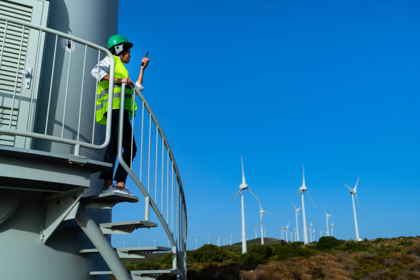 istock Young engineer woman with face mask looking and checking wind turbines at field during pandemic 1282046126