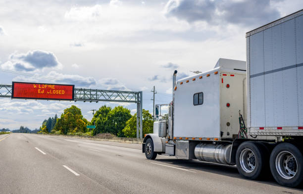 istock Classic white big rig semi truck with large cab sleeping compartment transporting cargo in dry van semi trailer running on the wide highway road 1282046887