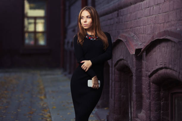 Young fashion woman in black sweater dress with a cell phone stock photo