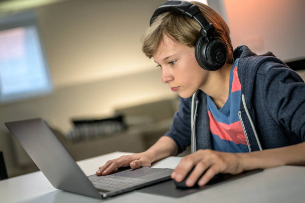 istock Young boy with headphones watching laptop computer screen. 1282054271