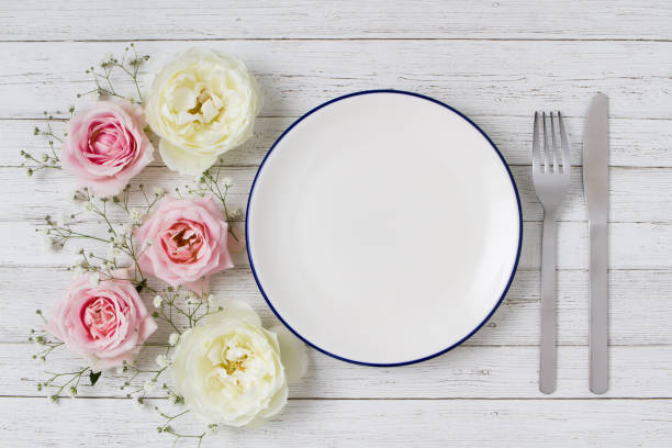 istock Plates and flowers on a white table 1282059626
