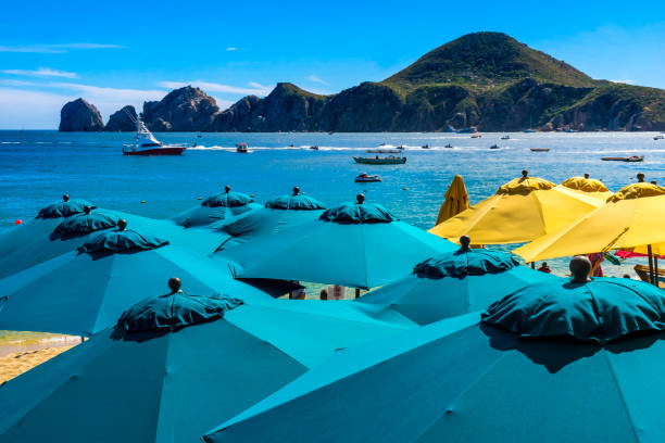 Blue Umbrellas Beach Restaurants Boats Cabo San Lucas Mexico Blue Umbrellas Colorful Beach Restaurants Boats Water Taxi Swimmers Cabo San Lucas Baja Mexico.  Los Cabos has many restaurants on sandy beaches. sea of cortes stock pictures, royalty-free photos & images