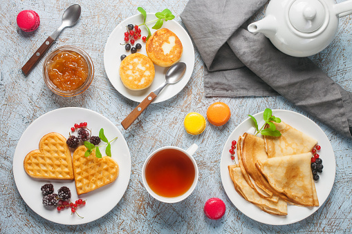 Breakfast - crepes, wafers and pancakes on white plates on a light background. Top view.