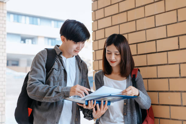 istock Students stand to read a book together on the campus. Education concept. 1282080319