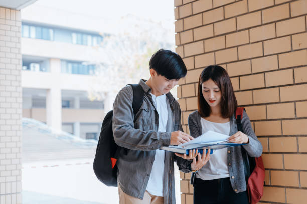 istock Students stand to read a book together on the campus. Education concept. 1282080328