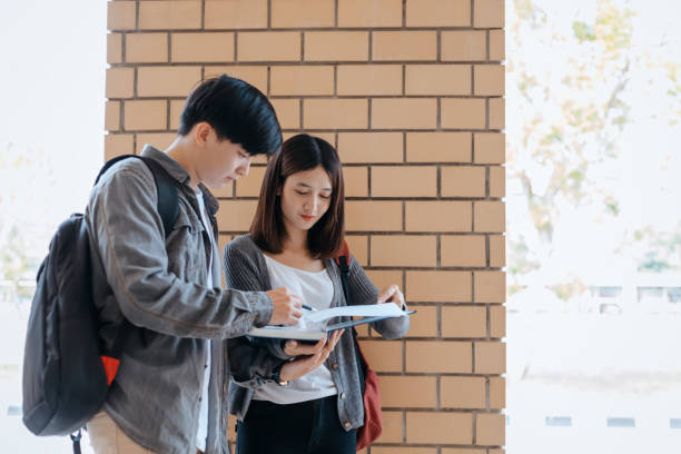 istock Students stand to read a book together on the campus. Education concept. 1282080330