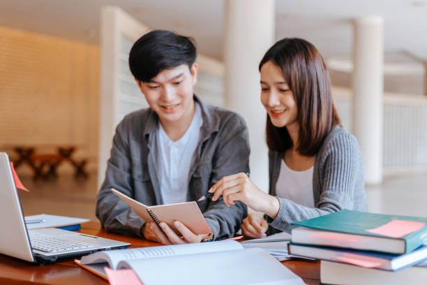 istock High school or college students  group catching up workbook and learning tutoring on desk and reading, doing homework, lesson practice preparing exam. 1282081003
