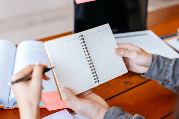 istock High school or college students  group catching up workbook and learning tutoring on desk and reading, doing homework, lesson practice preparing exam. 1282081008