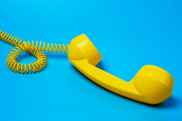 желтый ретро телефон приемник на синем фоне. - telephone telephone receiver phone cord telephone line стоковые фото и изображения