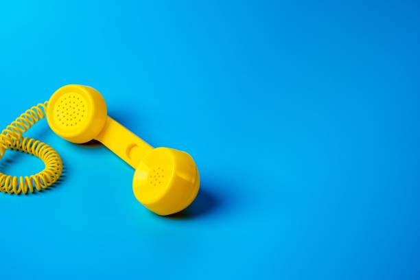 istock Yellow retro telephone receiver on blue background. 1282081077