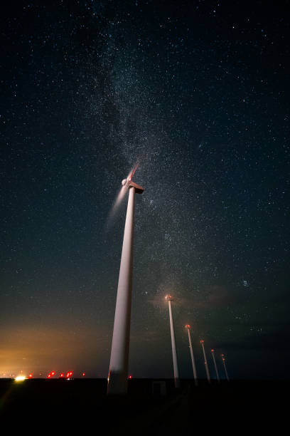 istock Renewable Energy Systems. Wind Turbine Power station park at night, working under the starry sky and the Milky way. Blurred motion. 1282082549
