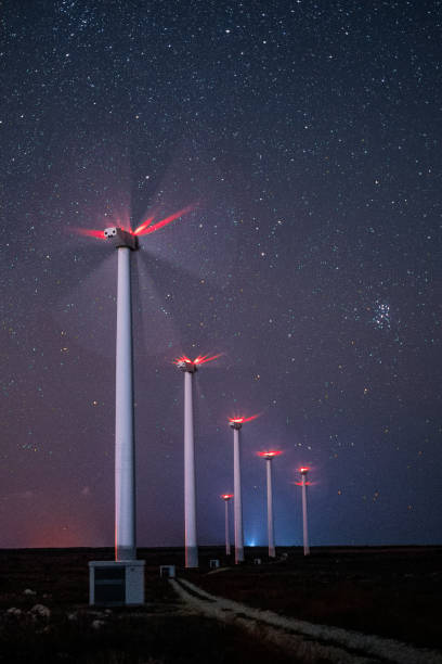 재생 에너지 시스템. 밤에는 풍력 터빈 발전소가 별이 빛나는 하늘과 은하수 아래에서 작업합니다. 흐린 동작. - industry dusk night sustainable resources 뉴스 사진 이미지