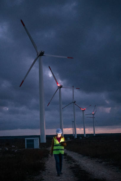 istock Renewable Energy Systems. Electricity Maintenance Engineer working on the field at a Wind Turbine Power station at dusk with a moody sky behind. Blurred motion. 1282082556