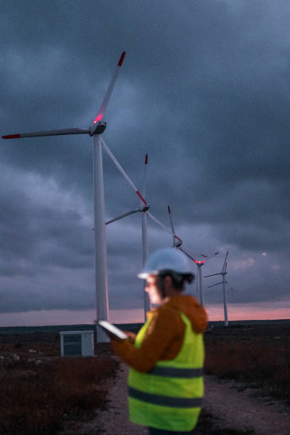 istock Renewable Energy Systems. Electricity Maintenance Engineer working on the field at a Wind Turbine Power station at dusk with a moody sky behind. Blurred motion. 1282082557