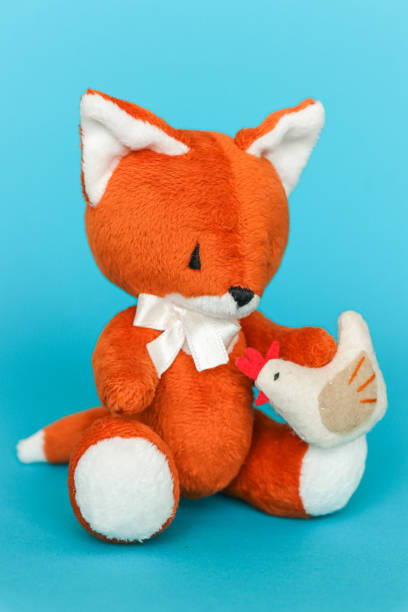 istock Soft toy ginger fox with chicken on a blue background. 1282083625