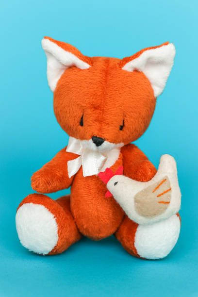istock Soft toy ginger fox with chicken on a blue background. 1282083640