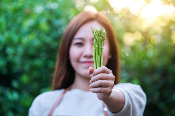 istock A woman holding and showing asparagus 1282085375