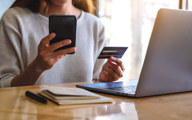 istock a woman holding credit card while using smart phone and laptop in office 1282085420