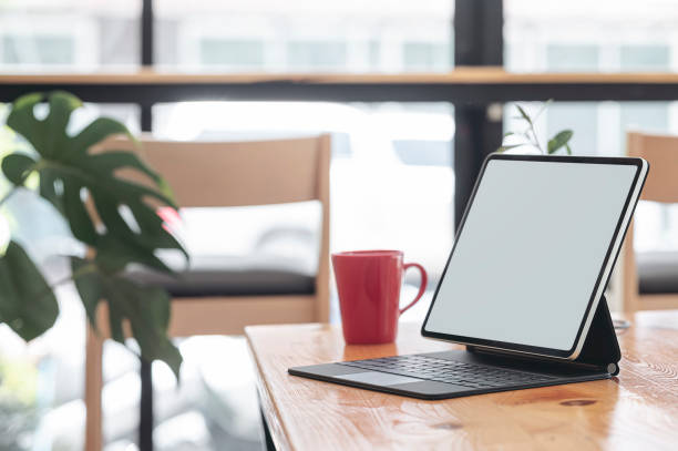 istock Mockup blank screen tablet with keyboard on wooden table in cafe, copy space. 1282091391