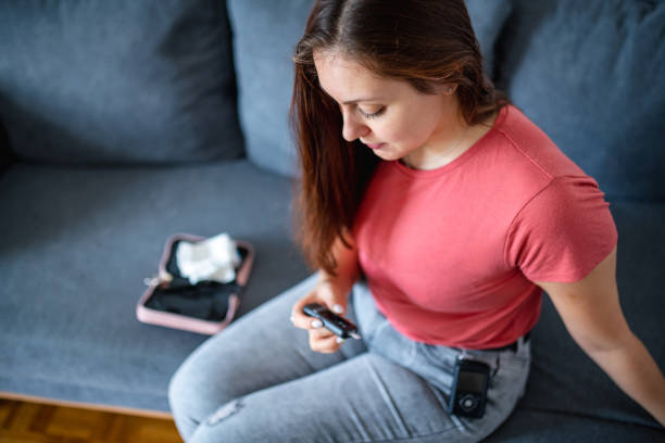 młoda kobieta na sobie pompy insulinowej i sprawdzanie glanukometr - meter blood sugar test glucose glaucometer zdjęcia i obrazy z banku zdjęć