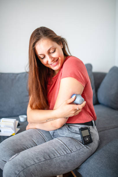 istock Young Woman with Type 1 Diabetes Applying Sensor to Arm 1282091604