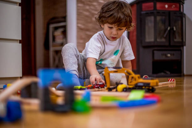 istock Little boy playing with a railroad train toy and plastic vehicle. 1282098016