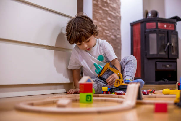 istock Little boy playing with a railroad train toy and plastic vehicle. 1282098028