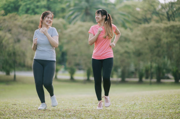 istock asian chinese young female warming up exercise in public park during weekend morning stretching bodies 1282101017