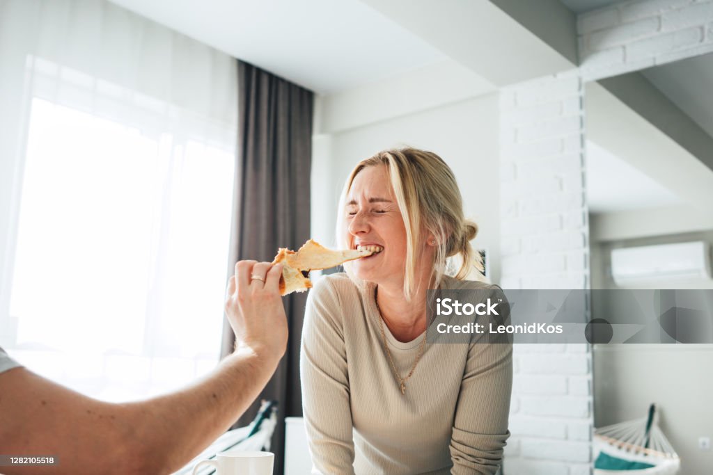 Glückliches Paar zu Hause machen Spaß und haben breafast im Bett. Junge Famile verbringen Zeit miteinander und füttern sich gegenseitig - Lizenzfrei Bett Stock-Foto