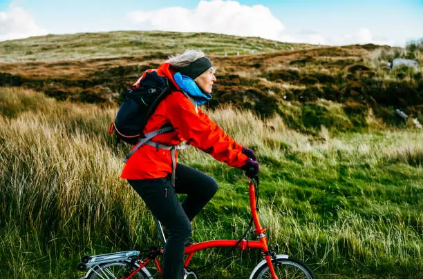 Woman cycling on North Uist, part of the Outer Hebrides of Scotland. Most of the roads are single lane and largely free from potholes, leaving the rider free to experience the volume of the islands. Real people doing real things in real places.