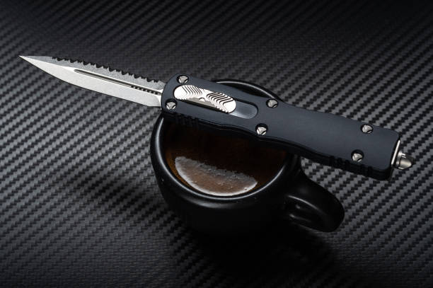 istock Knife on a coffee mug. Automatic knife and black coffee. Low key. 1282106433