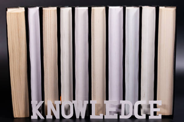 istock Books are arranged in a stack. The inscription at the bottom of knowledge. Dark background. 1282108799