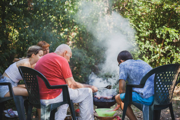 Man warming up over tea samovar and barbecue fire in the forest