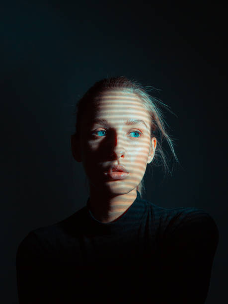 istock Mysterious portrait of girl with shadow pattern on her face in dark black studio 1282113644