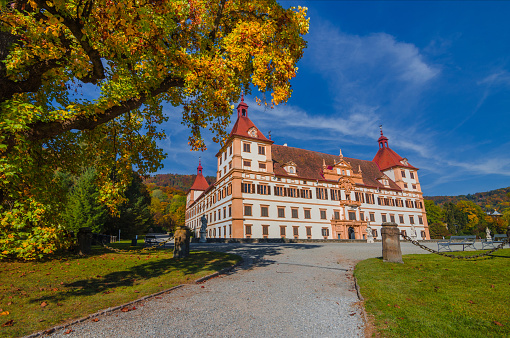 Graz, Austria-October 14, 2019: Colorful autumn colors, bright blue sky in the park and Eggenberg Palace in Graz, Styria region, Austria