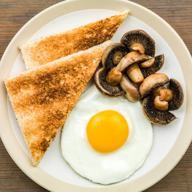 englisches frühstück mit sunny side up fried egg und pilzen mit toast - setzei stock-fotos und bilder