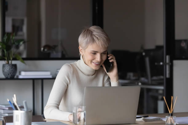 istock Smiling businesswoman work on computer talking on cell 1282120075