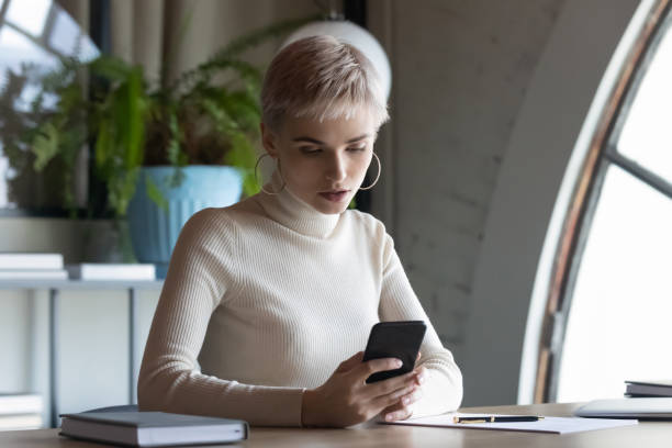 istock Young female employee using smartphone at workplace 1282120087