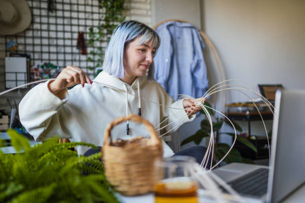 Young Blue haired woman knitting a wicker pot at home using laptop for watching online tutorial Young Blue haired woman knitting a wicker pot at home using laptop for watching online tutorial individual event stock pictures, royalty-free photos & images