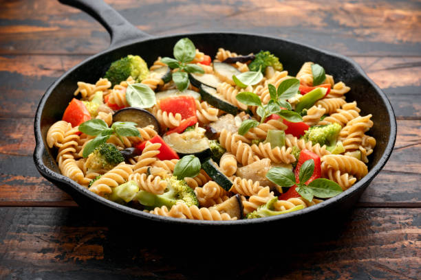 istock Fusilli pasta with vegetable, broccoli, zucchini, red pepper, eggplant and basil in iron cast pan 1282125076