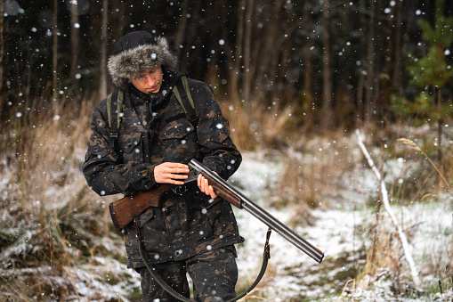 A hunter with a hunting gun in the winter forest