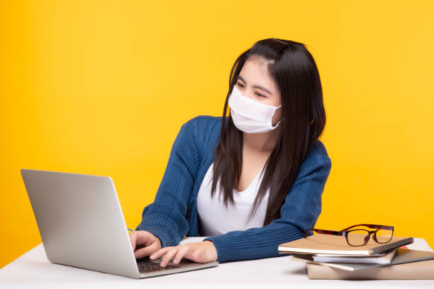istock Happy asian female college student wear protective face mask. Young student study lesson online while get quarantine at house, she study at home. Student girl working on laptop, study by herself 1282134089