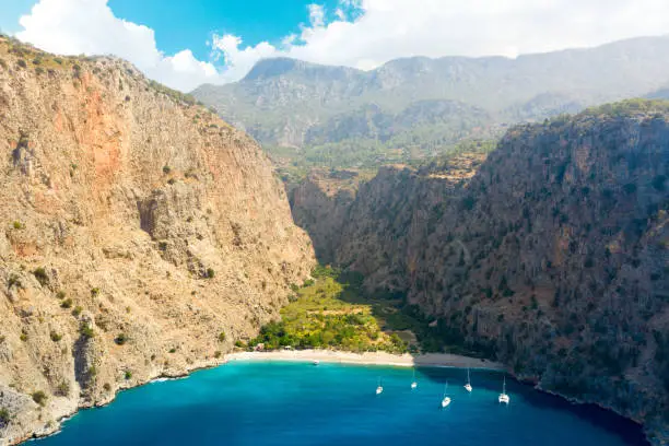 Photo of Aerial view over the clear beach and turquoise water of Butterfly Valley. In Turkish: Kelebekler Vadisi. Turkey