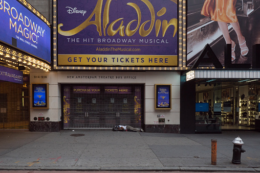 Manhattan, New York. October 22, 2020. A homeless man sleeps outside the entrance of the New Amsterdam Theatre box office on 42nd street.