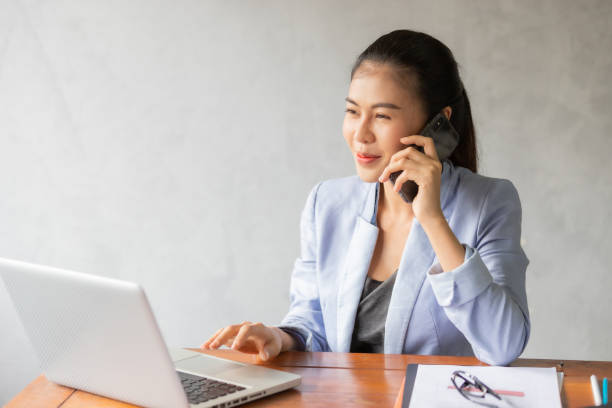 istock Business woman working on laptop while talking on phone 1282136464