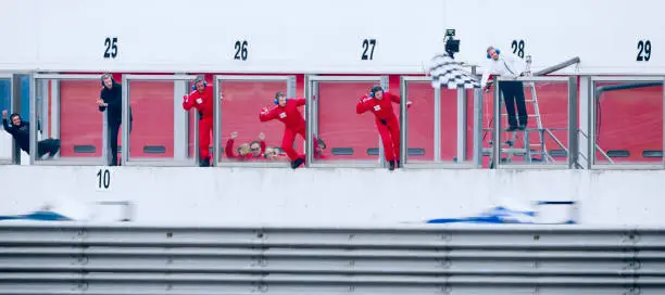 Pit crew members waiting for racing cars at pit stop.