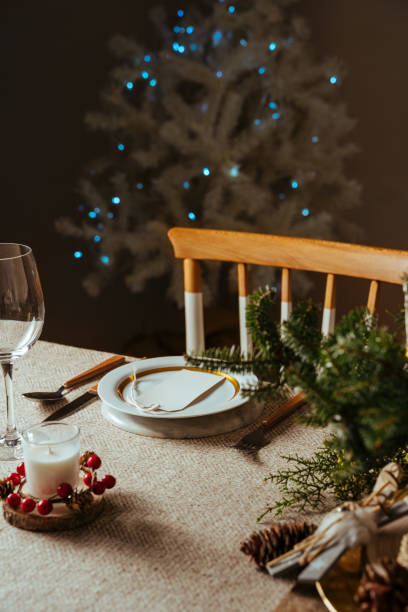 istock Homely christmas table setting, decorated with pine branches and rustic tablecloth in the living room of home tree lit background 1282140719